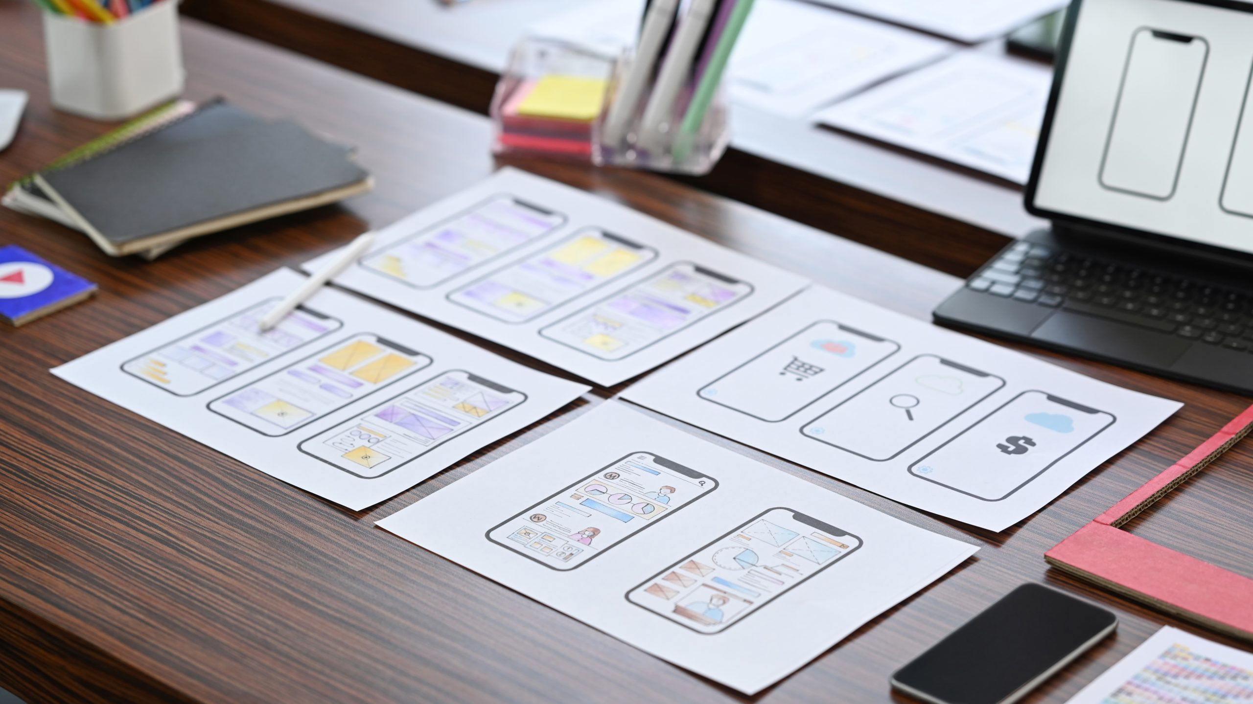 creative designer workplace with digital tablet wireframe sketches mobile application wooden table scaled